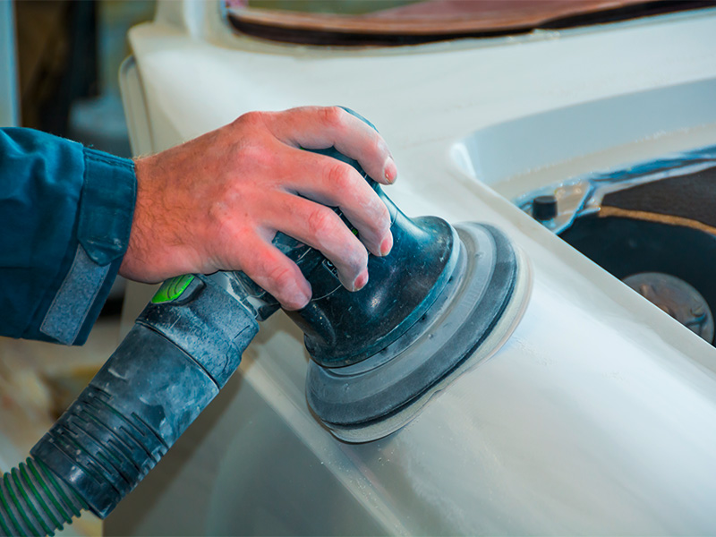 Lackierer mit Spritzpistole bei der Smart Repair Reparatur eines kleinen Fahrzeugschadens.