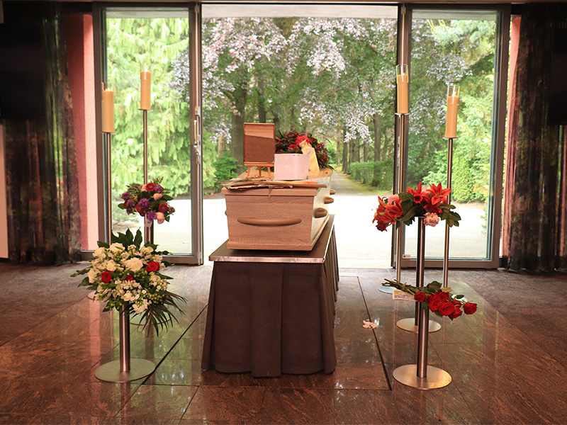 Sarg mit Blumenarrangement in einer Trauerhalle – symbolisiert würdevolle Bestattung in Hagen.