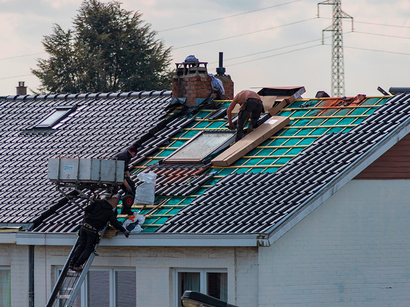 Handwerker arbeiten an der Dacheindeckung in Hagen und bringen Isolierung und Dachmaterial auf einem Wohnhausdach an. 