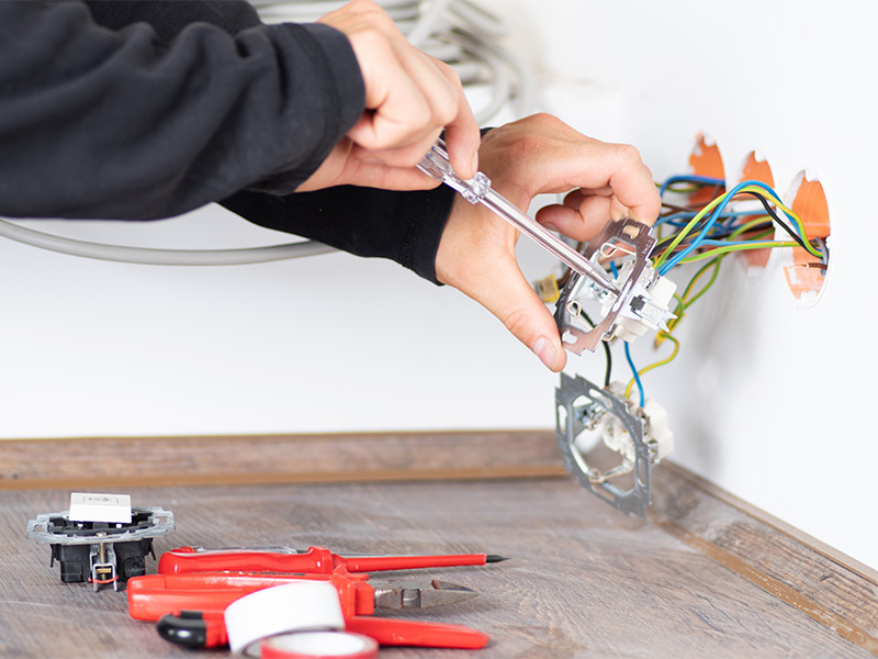 Elektriker führt Elektroprüfung an Steckdose durch, misst Spannung und Sicherheit in Haus- oder Geschäftsinstallation präzise