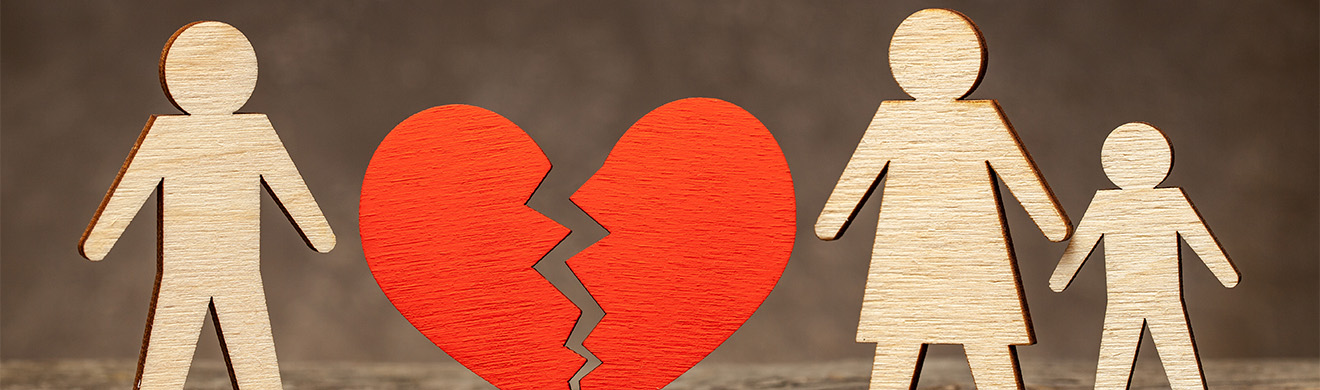 Holzfiguren Mann, Frau, Kind mit zerbrochenem Herz dazwischen – symbolisiert Scheidung, Beratung beim Anwalt für Scheidung in Hagen.
