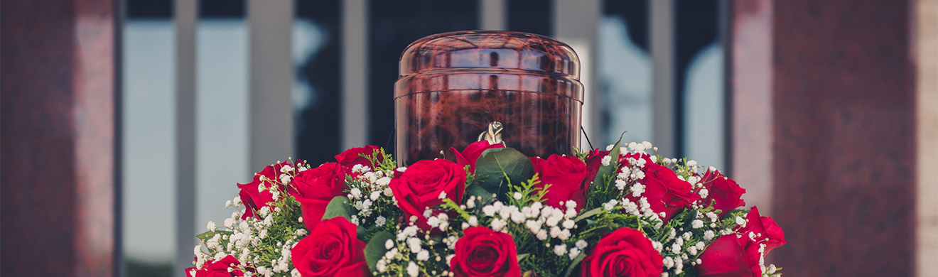 Urne mit Asche und weißen Blumen auf einer Trauerfeier als stiller Abschied bei einer Feuerbestattung in Hagen