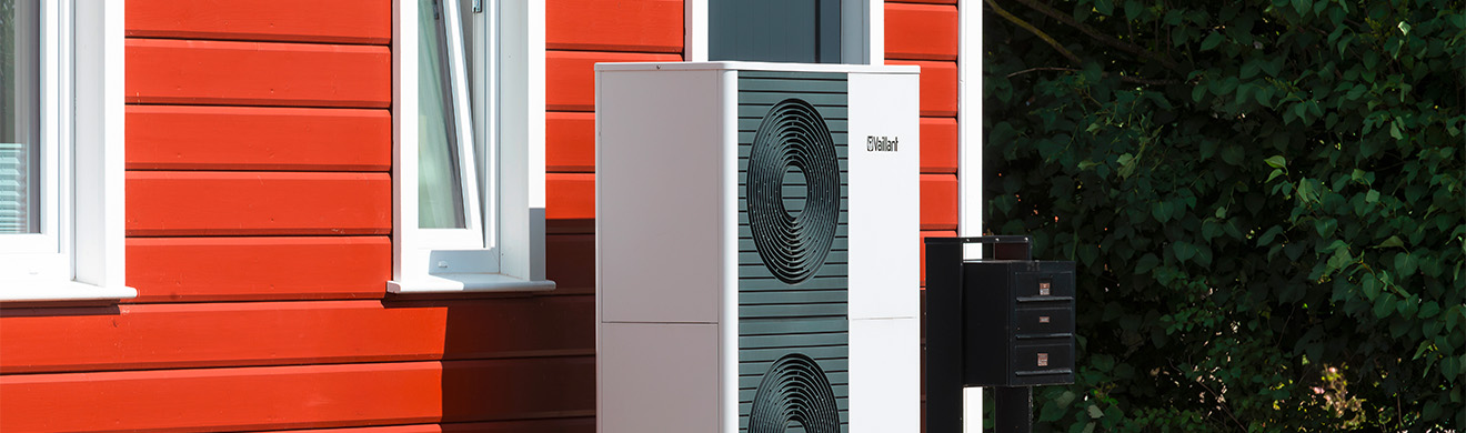 Luft Wasser Wärmepumpe vor rotem Holzhaus in Gevelsberg als Beispiel für effiziente Heizungsmodernisierung.