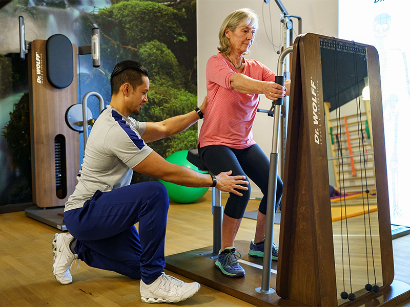 Training Beinmuskel einer älteren Dame am Fitnessgerät durch Fitnesstrainer in Hagen