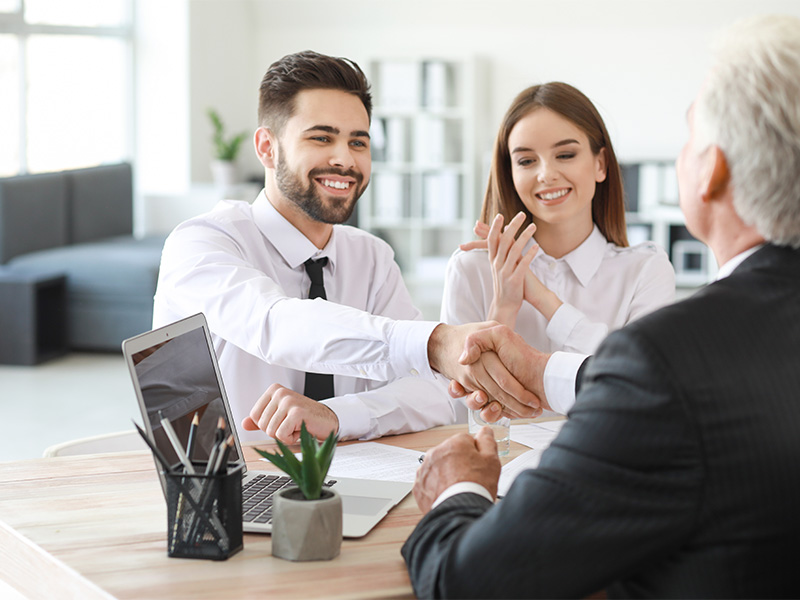 Ehepaar schließt Notarvertrag beim Notar ab und schüttelt die Hand des Notars – rechtliche Sicherheit des Vertrags Notarvertrag.