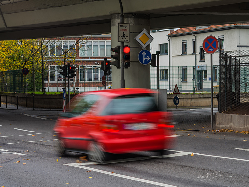 Rotes Auto überfährt bei Rot eine Ampel und zeigt eine typische Situation mit Bezug zu Fahrverbot in Gevelsberg.