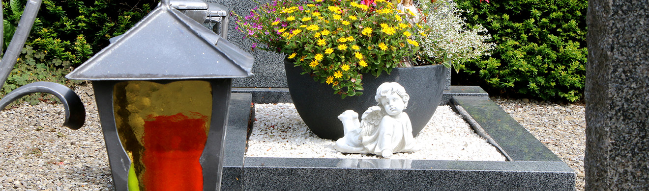 Grab mit Sommerblumen, Engelstatue und Laterne auf Friedhof – symbolisch für Vorsorgevertrag in Hagen.